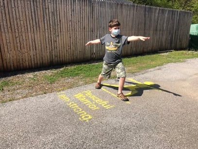 boy using a warrior pose yoga pose on the sidewalk