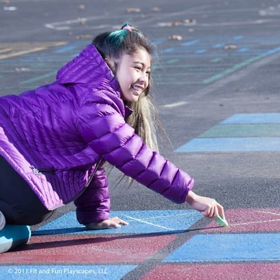 young girl drawing with chalk on a blacktop space