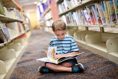 child reading a book in the library