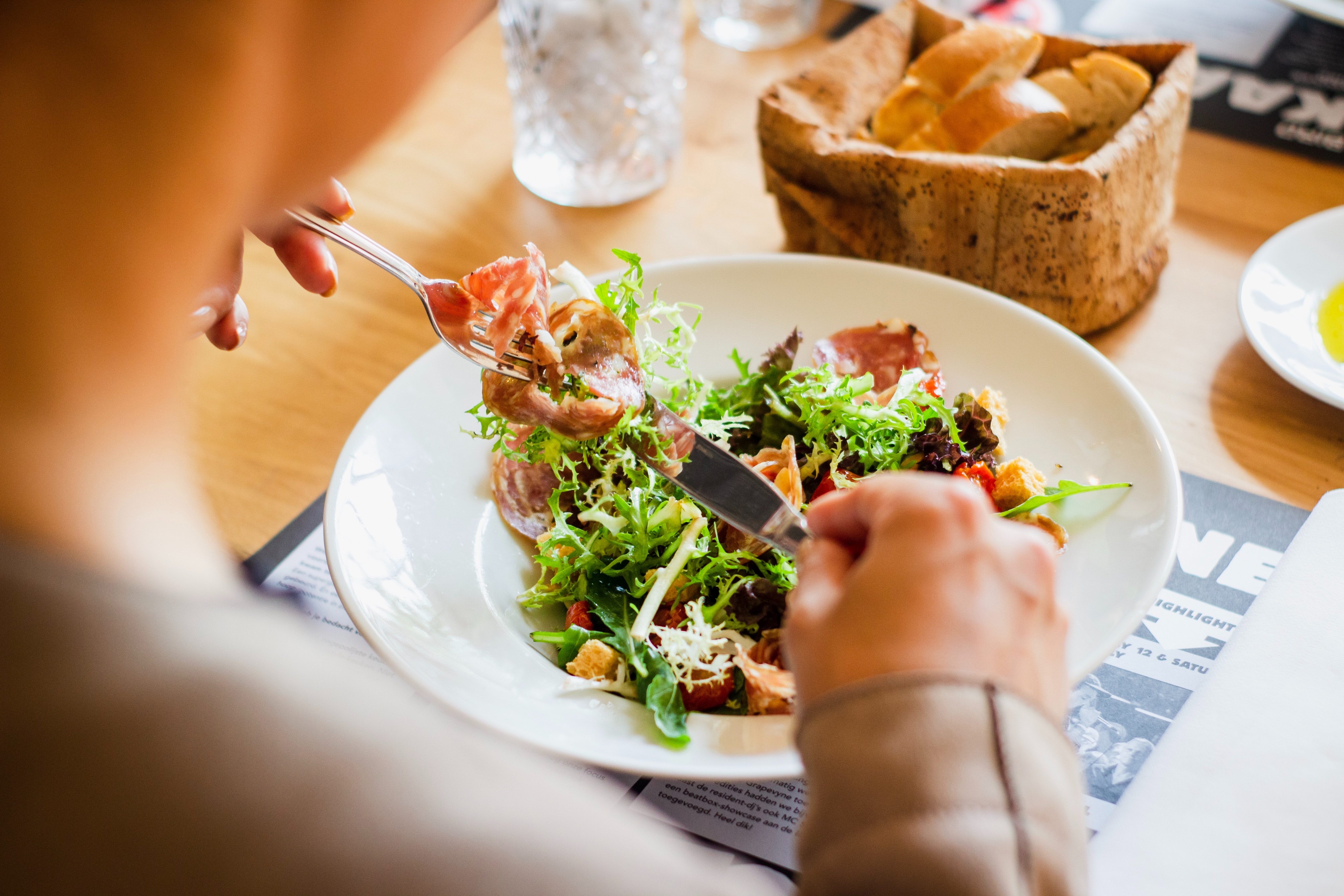 Alt: A person eating a dish with greens. Image courtesy of Unsplash, by Louis Hansel.