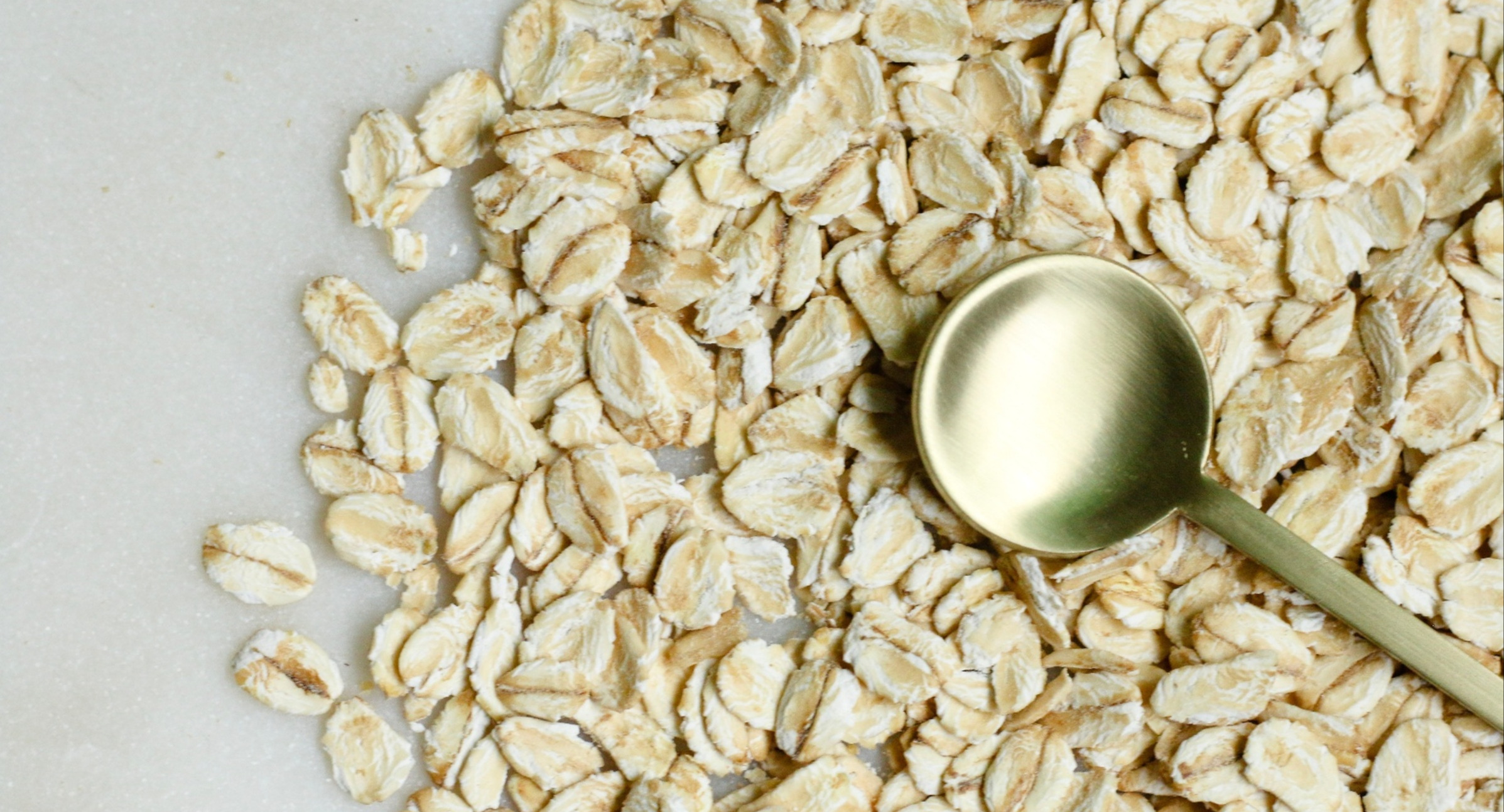 Alt: Rolled oats and a small spoon up close on a table. Image courtesy of Unsplash, by Melissa Di Rocco.