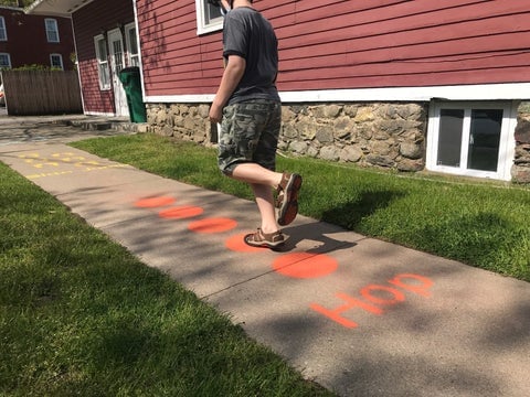 boy hopping on painted sidewalk markings that read "hop" and have circles