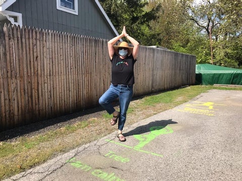 woman doing a tree pose over a painted sidewalk marking