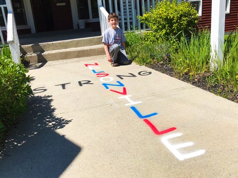 boy kneeling next to sidewalk lettering